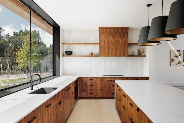 kitchen with backsplash, sink, decorative light fixtures, stovetop, and light hardwood / wood-style floors