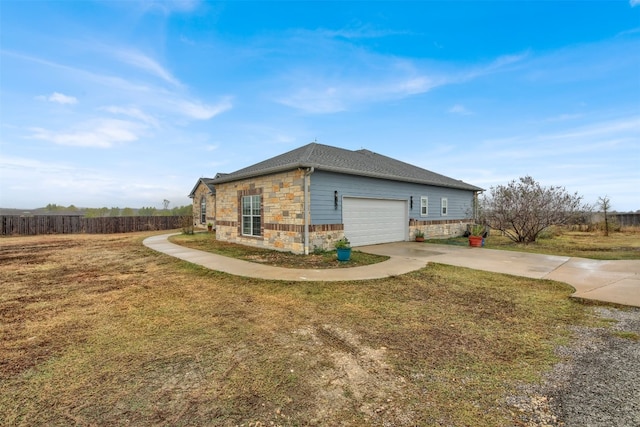 view of home's exterior featuring stone siding, a lawn, driveway, and fence