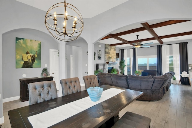 dining room with coffered ceiling, ceiling fan with notable chandelier, beam ceiling, light hardwood / wood-style flooring, and a fireplace