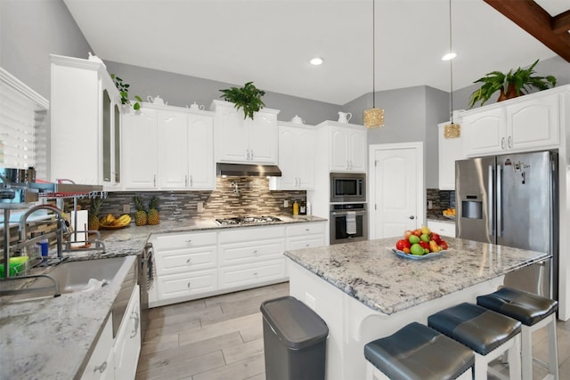 kitchen with stainless steel appliances, decorative light fixtures, a sink, and white cabinetry