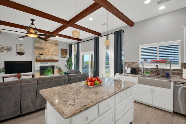 kitchen with a sink, white cabinetry, open floor plan, stainless steel dishwasher, and a center island