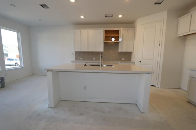 kitchen featuring a center island with sink, white cabinets, sink, and tasteful backsplash