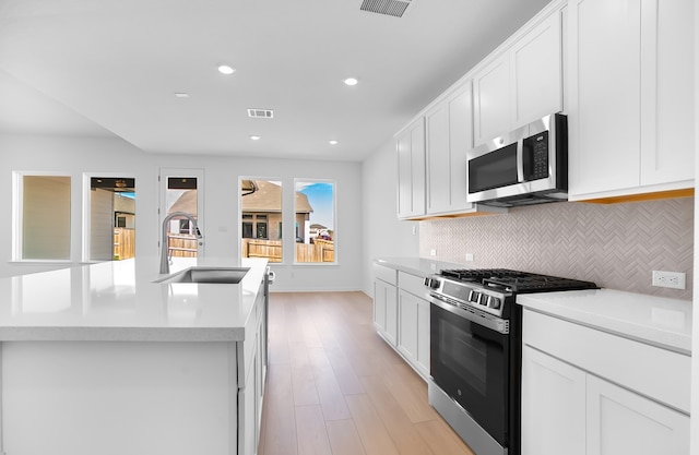 kitchen with visible vents, a sink, light countertops, appliances with stainless steel finishes, and backsplash