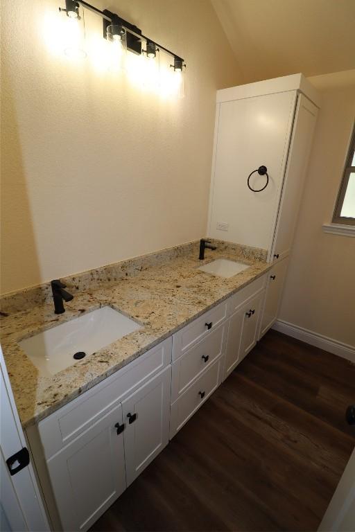 bathroom with wood-type flooring, vanity, and lofted ceiling