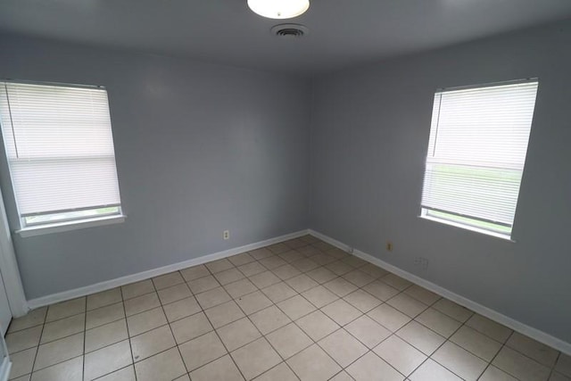 tiled spare room with a healthy amount of sunlight