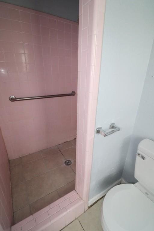 bathroom with tile patterned floors, toilet, and tiled shower