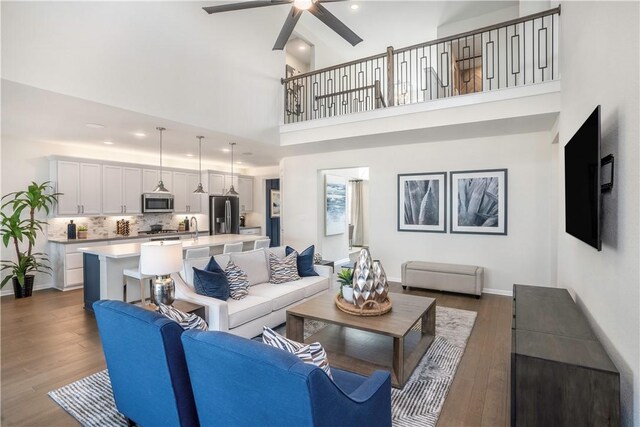 living room featuring dark hardwood / wood-style floors, high vaulted ceiling, ceiling fan, and sink