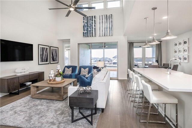 living room featuring ceiling fan, sink, dark wood-type flooring, and a high ceiling