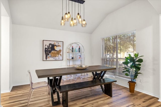 dining space featuring wood-type flooring, an inviting chandelier, and vaulted ceiling