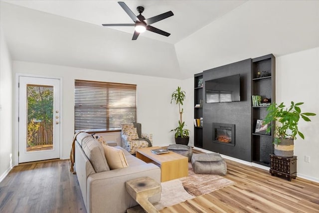 living room featuring ceiling fan, a fireplace, wood-type flooring, and lofted ceiling