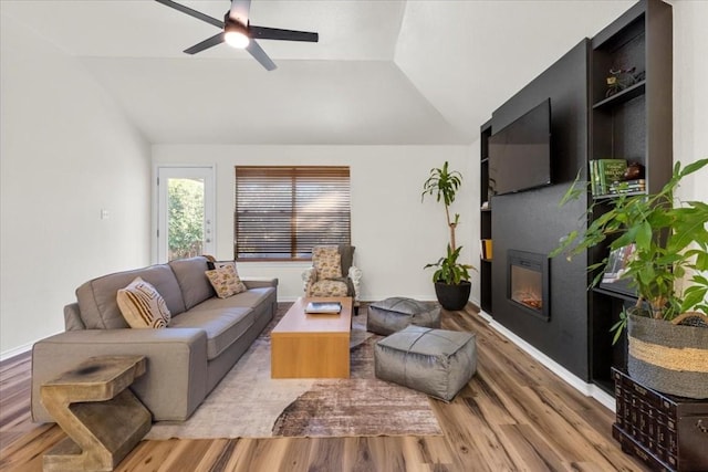 living room with light hardwood / wood-style floors, ceiling fan, and lofted ceiling