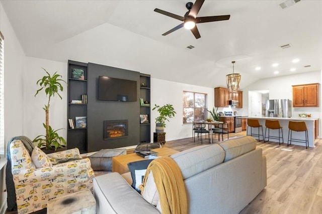 living room featuring light hardwood / wood-style flooring, ceiling fan with notable chandelier, and lofted ceiling