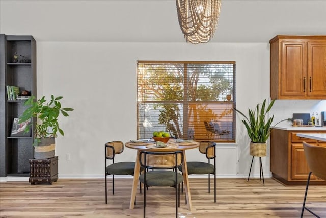 dining space with light hardwood / wood-style floors and an inviting chandelier