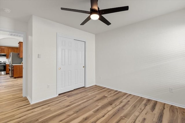 unfurnished bedroom featuring stainless steel fridge, ceiling fan, a closet, and light hardwood / wood-style floors