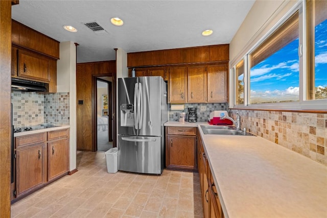 kitchen featuring backsplash, black electric cooktop, stainless steel fridge with ice dispenser, and sink