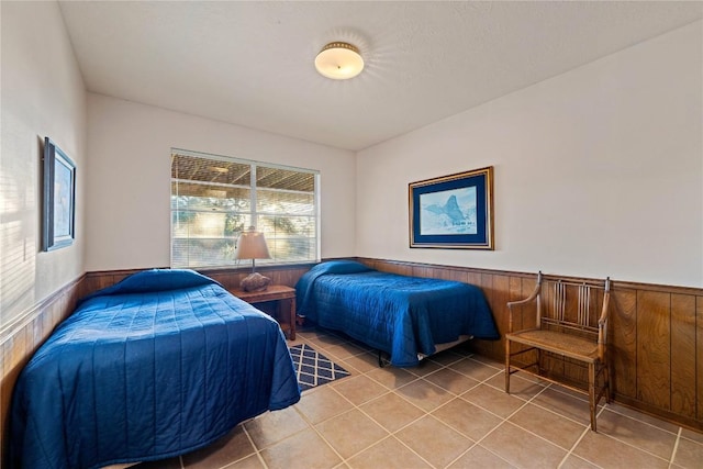 bedroom featuring tile patterned flooring and wood walls