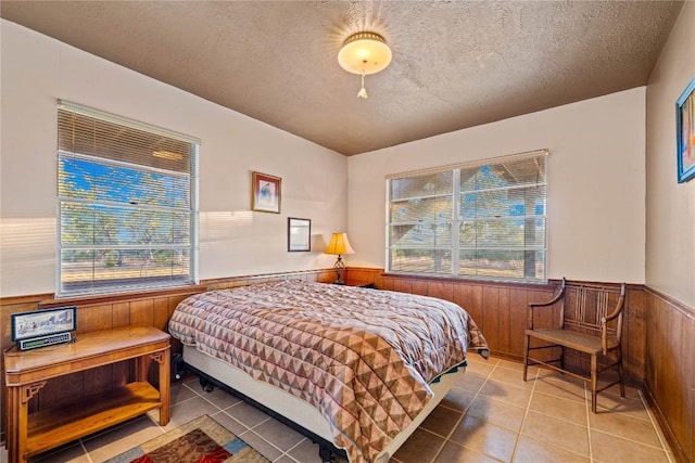 tiled bedroom featuring a textured ceiling and wooden walls