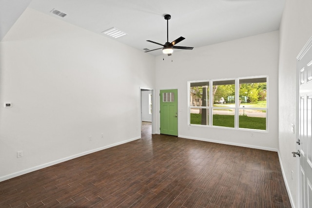 empty room featuring a towering ceiling, dark hardwood / wood-style floors, and ceiling fan