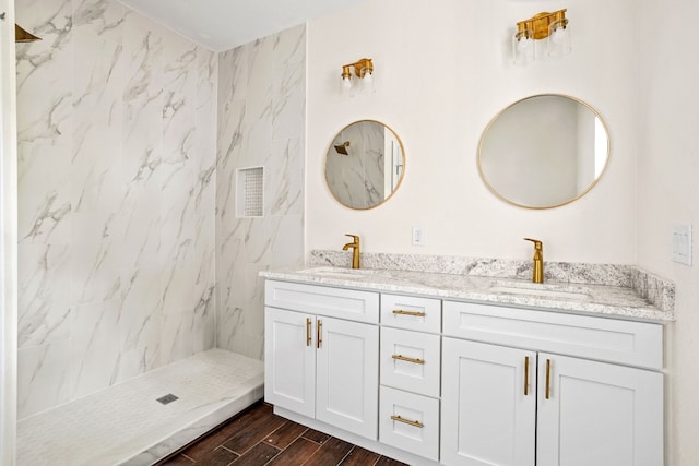 bathroom with hardwood / wood-style floors, vanity, and a tile shower