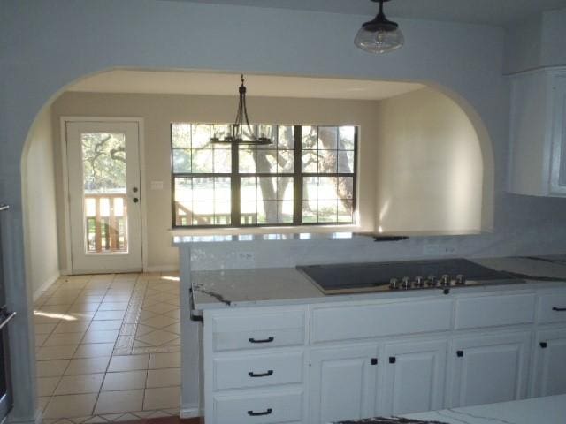 kitchen with light tile patterned floors, tasteful backsplash, white cabinetry, and hanging light fixtures