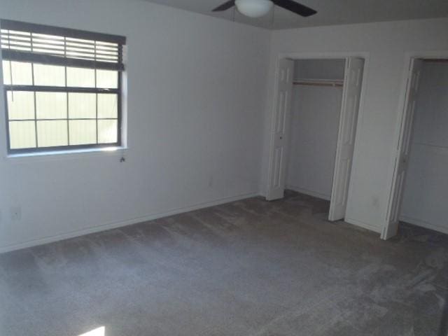 unfurnished bedroom featuring ceiling fan, dark carpet, and a closet