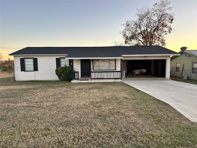 ranch-style house featuring covered porch, a yard, and a garage