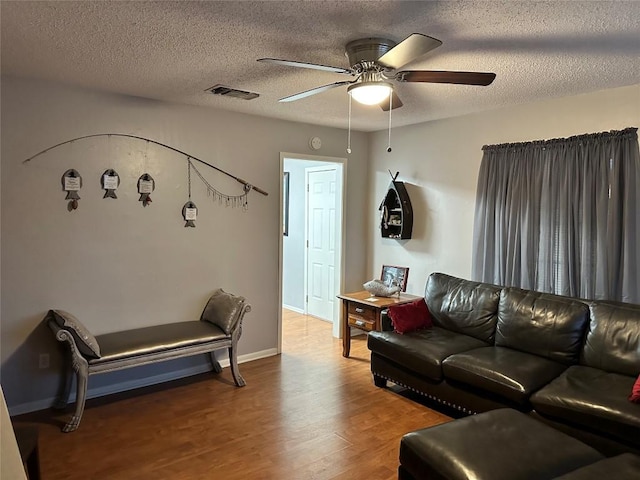 living room featuring ceiling fan, wood-type flooring, and a textured ceiling