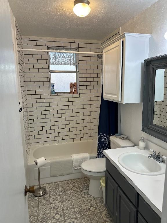 full bathroom with vanity, shower / bath combination with curtain, a textured ceiling, and toilet