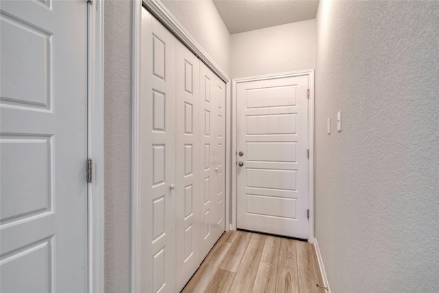 hallway featuring light hardwood / wood-style floors and a textured ceiling