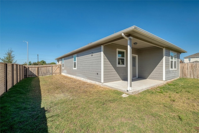 back of house with a patio area and a lawn