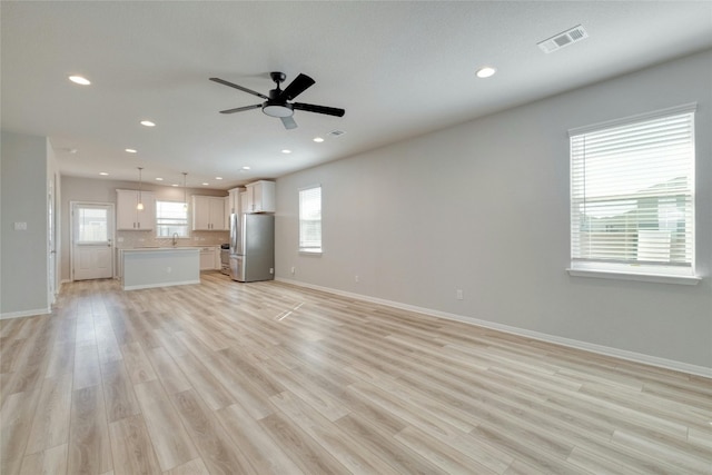 unfurnished living room featuring a wealth of natural light and light hardwood / wood-style floors