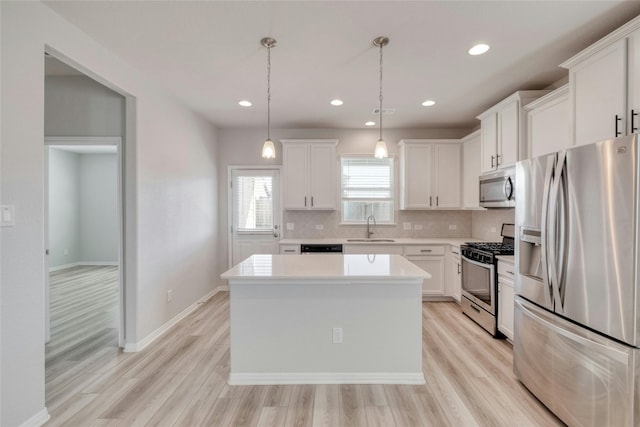 kitchen featuring pendant lighting, light hardwood / wood-style floors, appliances with stainless steel finishes, a kitchen island, and white cabinetry