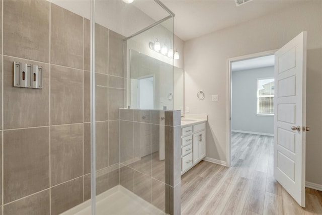 bathroom with tiled shower, hardwood / wood-style floors, and vanity