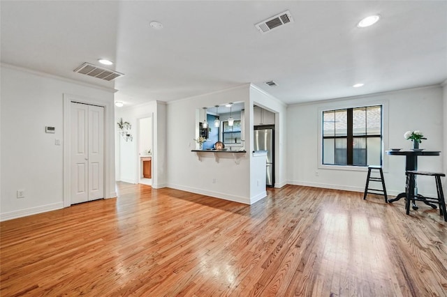 unfurnished living room featuring light hardwood / wood-style floors and crown molding