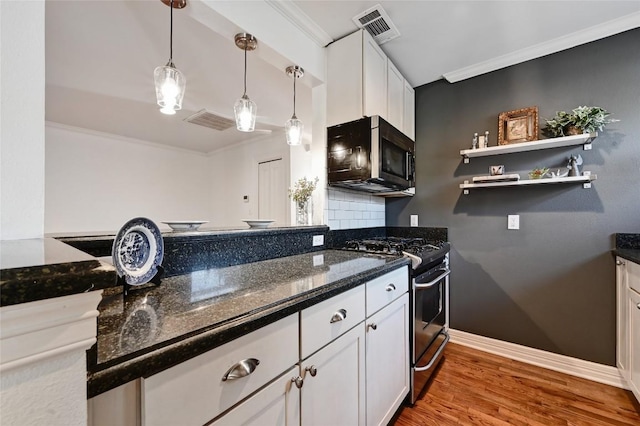 kitchen featuring gas stove, backsplash, white cabinetry, and dark stone counters