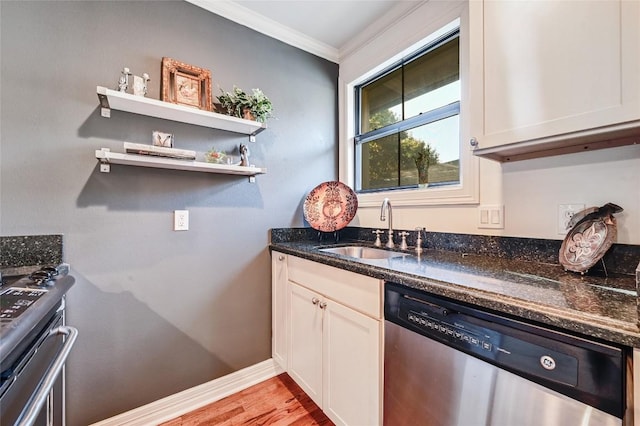 kitchen featuring appliances with stainless steel finishes, ornamental molding, sink, white cabinets, and light hardwood / wood-style floors