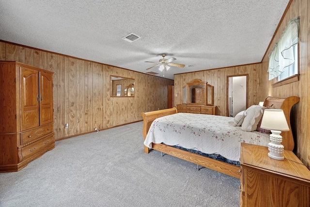 bedroom with light carpet, a textured ceiling, ceiling fan, and wood walls