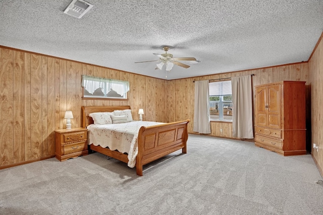 bedroom featuring ceiling fan, light colored carpet, a textured ceiling, and wooden walls