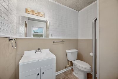 bathroom with vanity, toilet, and a textured ceiling