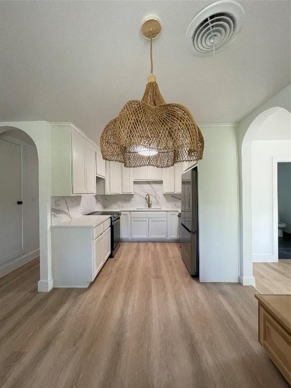 kitchen with arched walkways, black electric range, a sink, and freestanding refrigerator