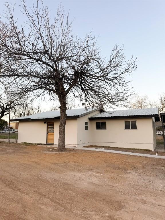 back of property with metal roof and stucco siding