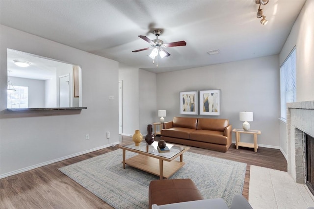 living room with visible vents, a fireplace, baseboards, and wood finished floors