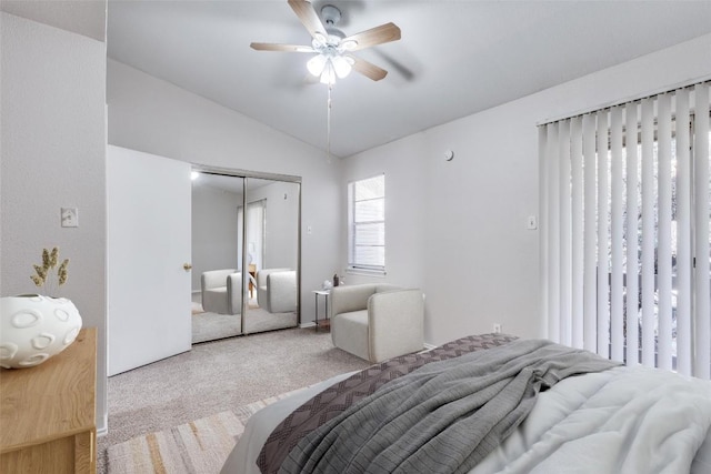 bedroom with a ceiling fan, lofted ceiling, a closet, and light carpet