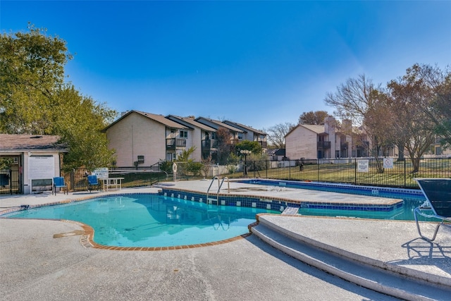 community pool with a residential view, fence, and a community hot tub