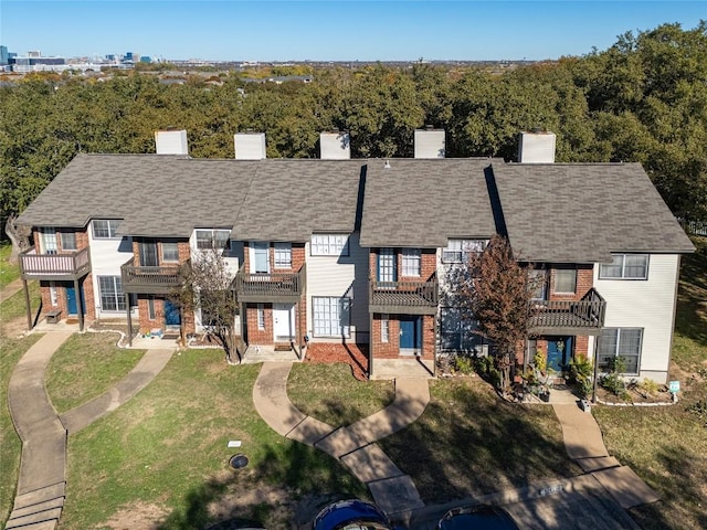 multi unit property with brick siding, a chimney, and a front lawn