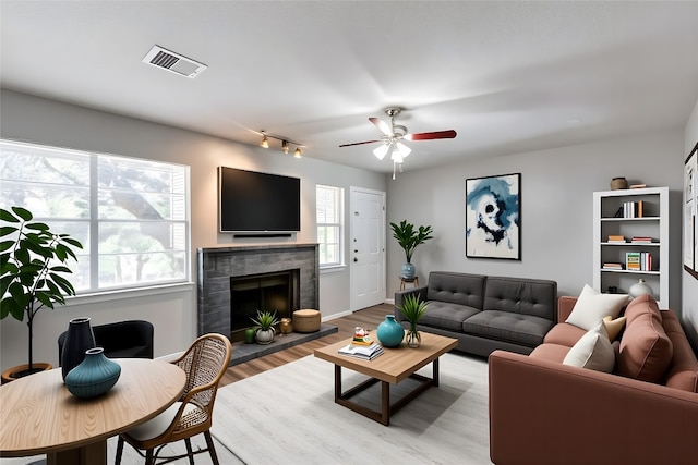 1815 River Crossing Cir Unit D, Austin, TX 78741 - living area with a tile fireplace, a ceiling fan, light wood-type flooring, and rail lighting