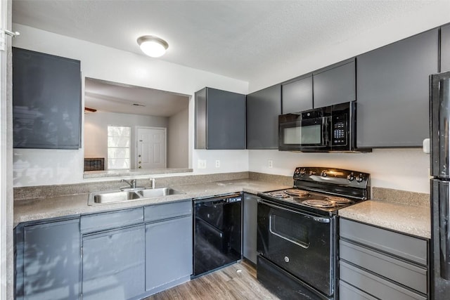 1815 River Crossing Cir Unit D, Austin, TX 78741 - kitchen with black appliances, a sink, light wood-style flooring, and gray cabinetry