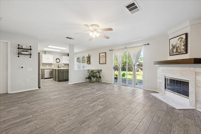 unfurnished living room featuring ceiling fan, sink, and light hardwood / wood-style floors