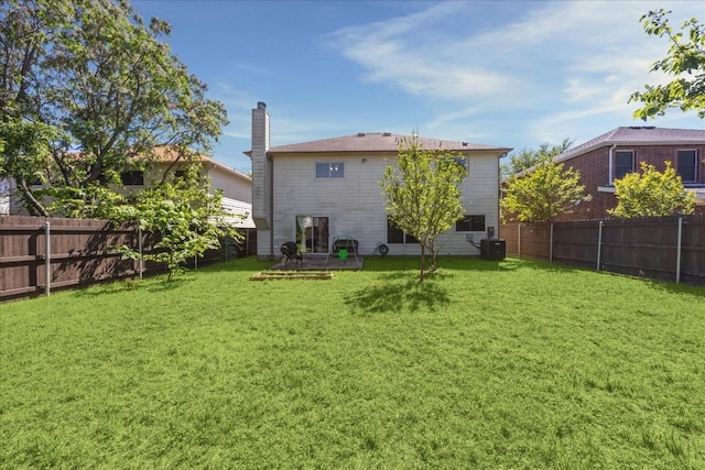 rear view of property featuring a lawn and central AC unit