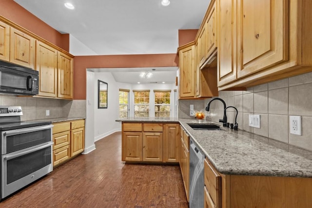 kitchen with backsplash, sink, appliances with stainless steel finishes, dark hardwood / wood-style flooring, and light stone counters